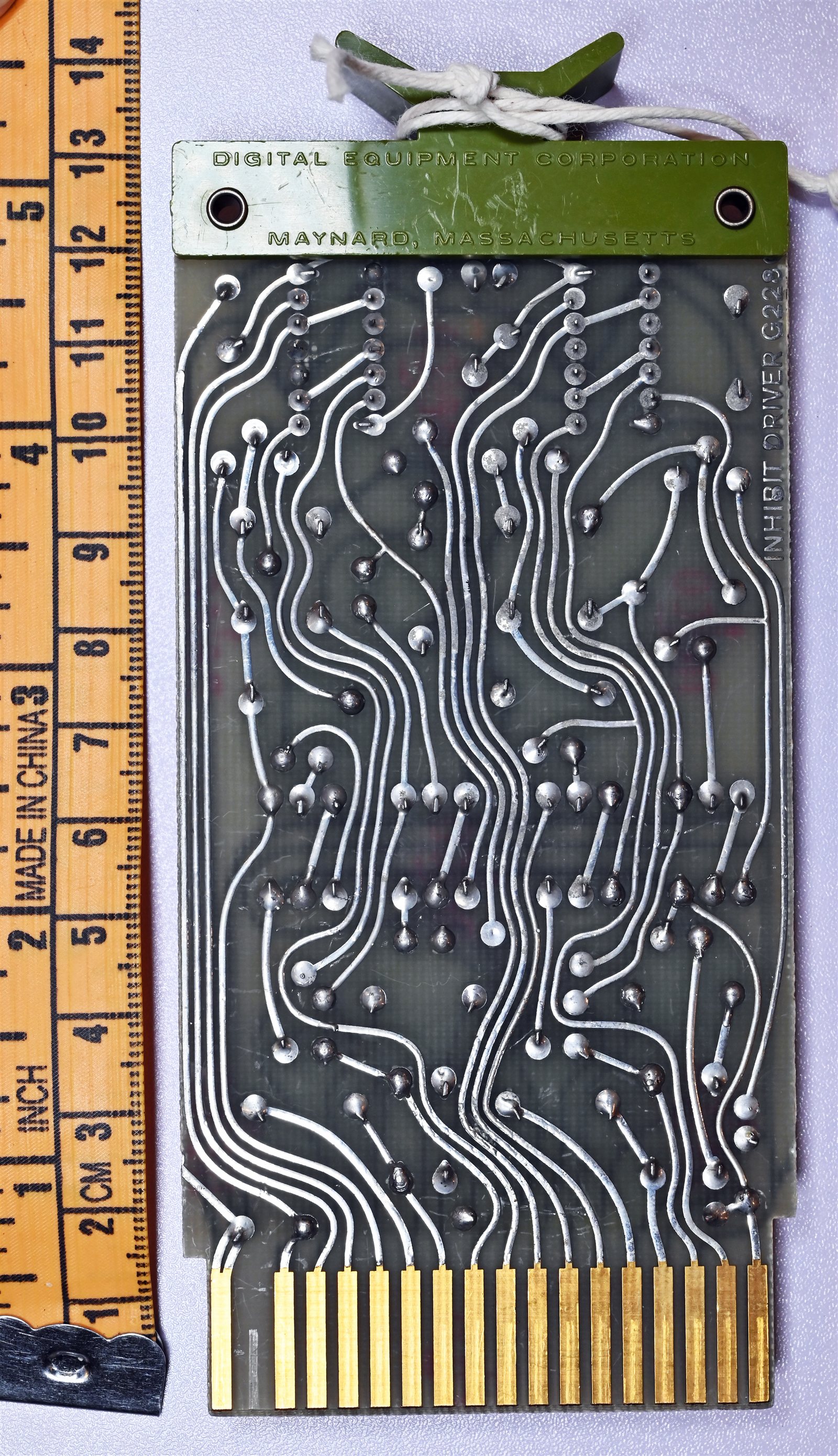 The back of a DEC flip-chip module — a small printed-circuit card whose logic components are wired out to the row of gold-plated contacts along its bottom edge, the edge connector that plugs the ca…